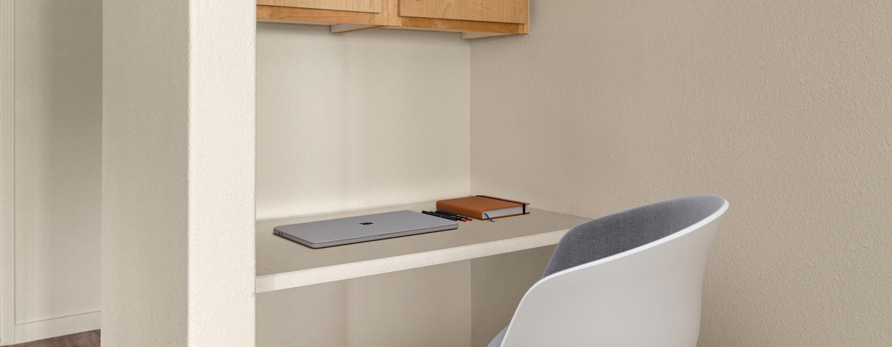 a desk with a chair and a laptop on it