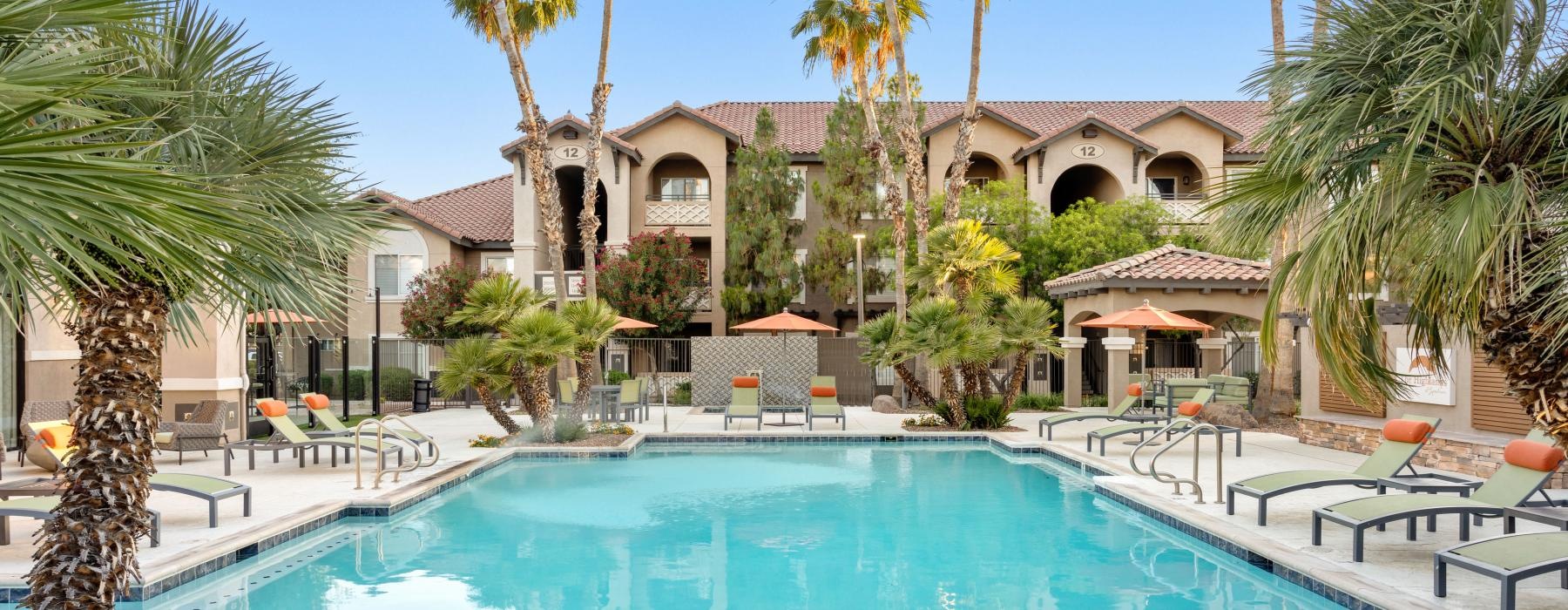 a swimming pool with palm trees and apartment building in the background